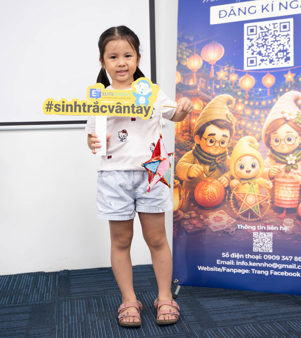 Bé gái cầm lồng đèn ngôi sao mini và bảng hashtag sinh trắc vân tay chụp hình lưu niệm.