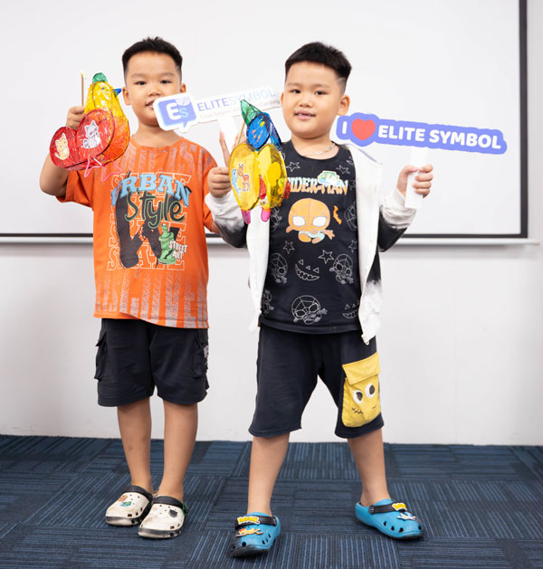 Hai bé trai cầm bảng tên Sinh Trắc Vân Tay Elite Symbol tạo dáng tinh nghịch cùng lồng đèn tự làm.