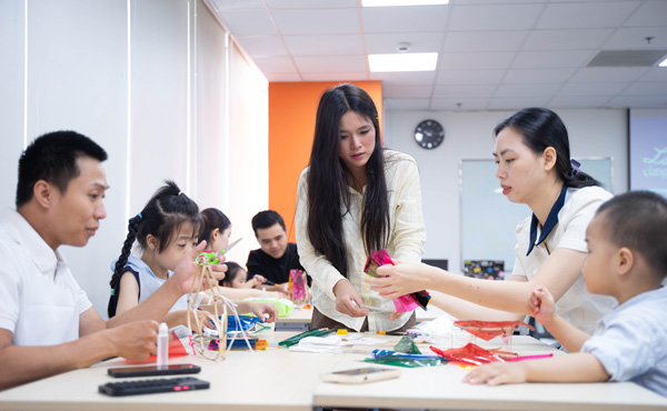 Bàn workshop đông vui với phụ huynh và các bé đang chăm chú dán giấy lồng đèn truyền thống.