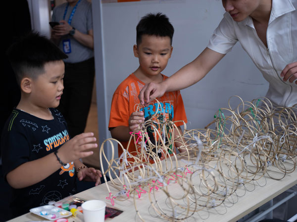 Hai bé trai đang chăm chú chọn khung tre lồng đèn thủ công tại bàn workshop.